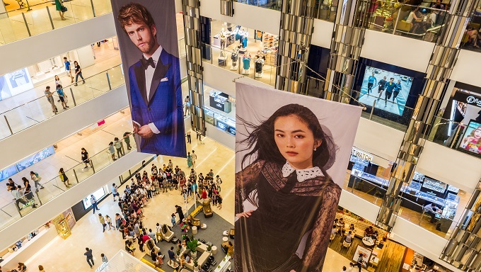 Multistory interior of Saigon Center with two large advertising placards showing portraits of models. Photo by Shutterstock/David Bokuchava.